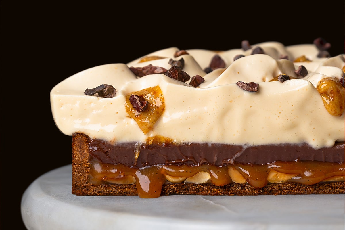 découpe de tarte au chocolat, cacahuètes et caramel