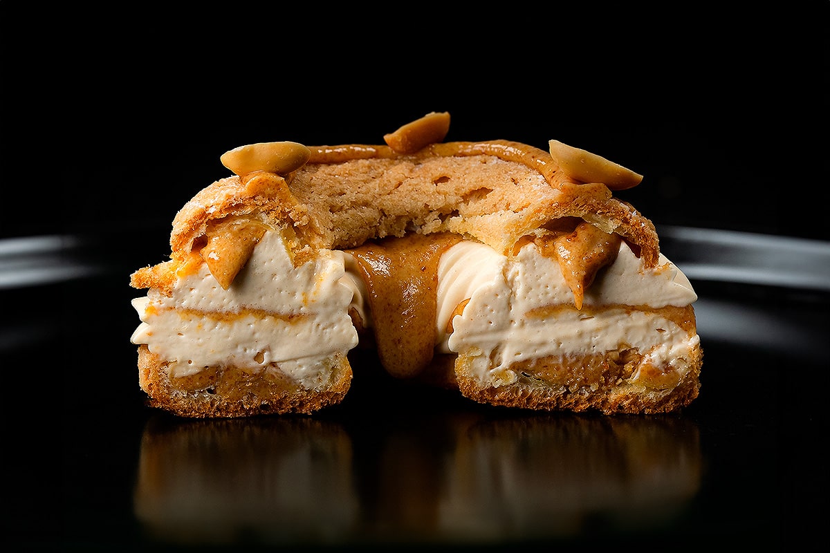 paris brest aux cacahuètes coupé en deux sur fond noir