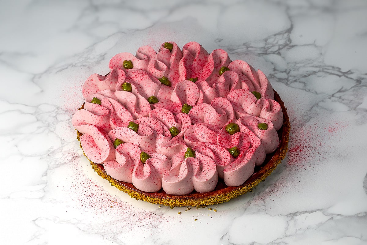 tarte pistache framboise posée sur un fond de marbre